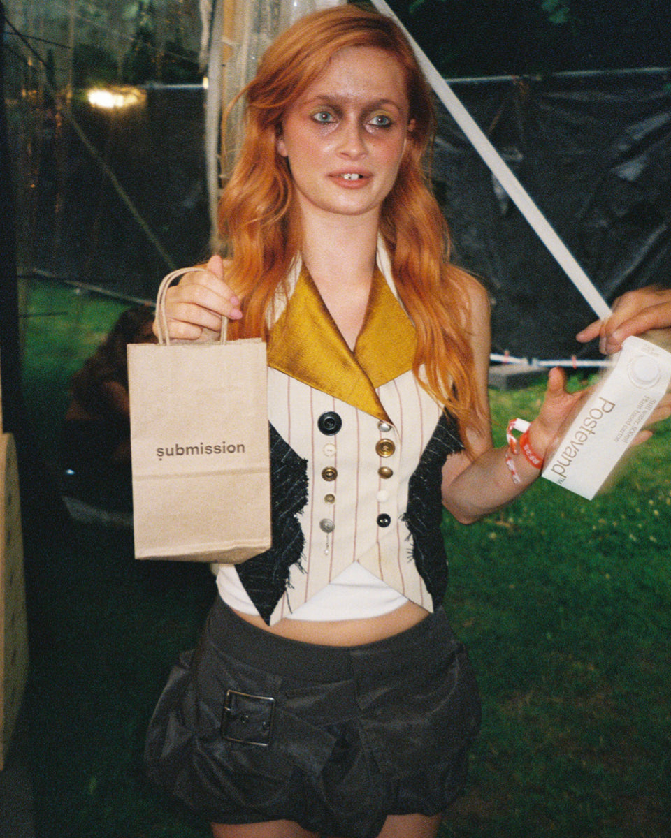 Person holding a 'submission beauty' bag and a product box with a blurred background