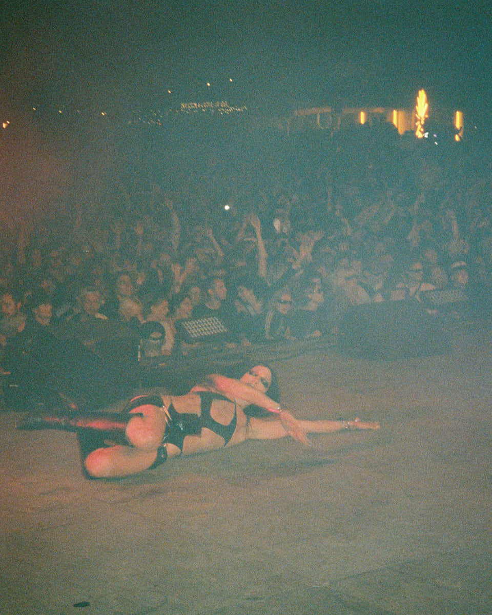 DjG2g Performance at roskilde festival in a black and red outfit on a stage with a crowd in the background.