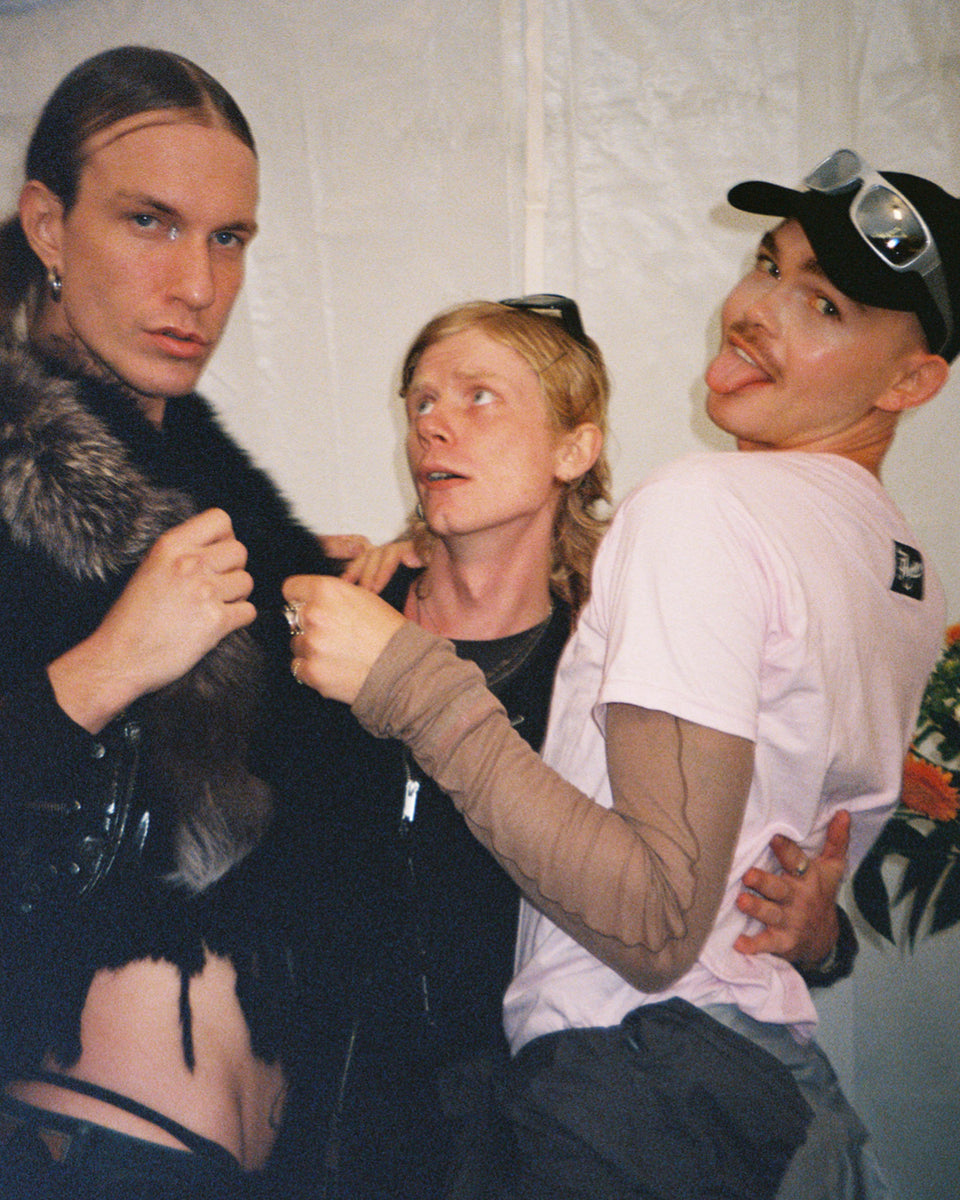 Three people posing together against a plain background