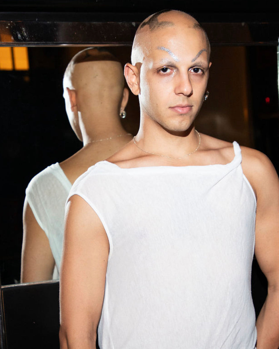Person wearing a white sleeveless top with a blurred background