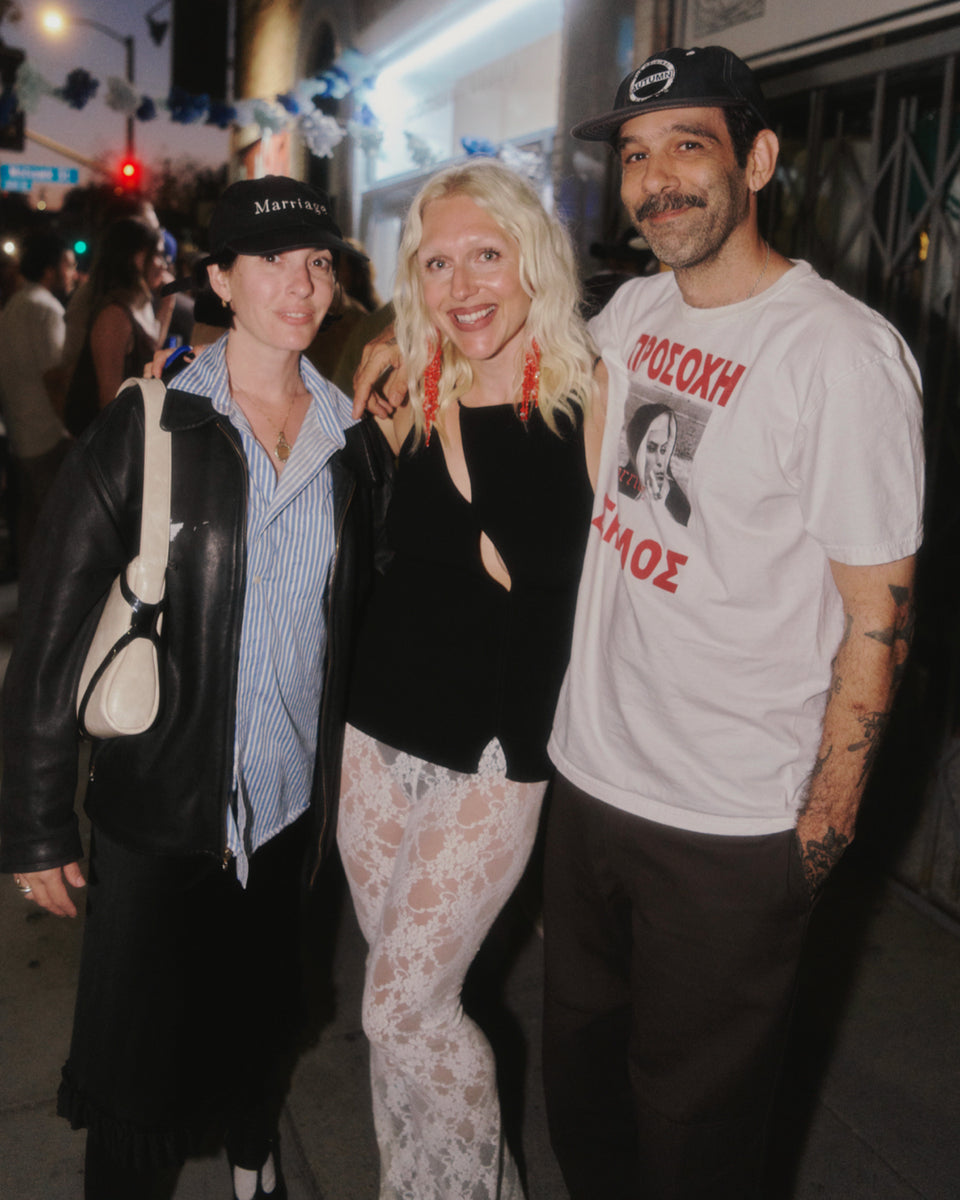 Three people posing together on a street at night.