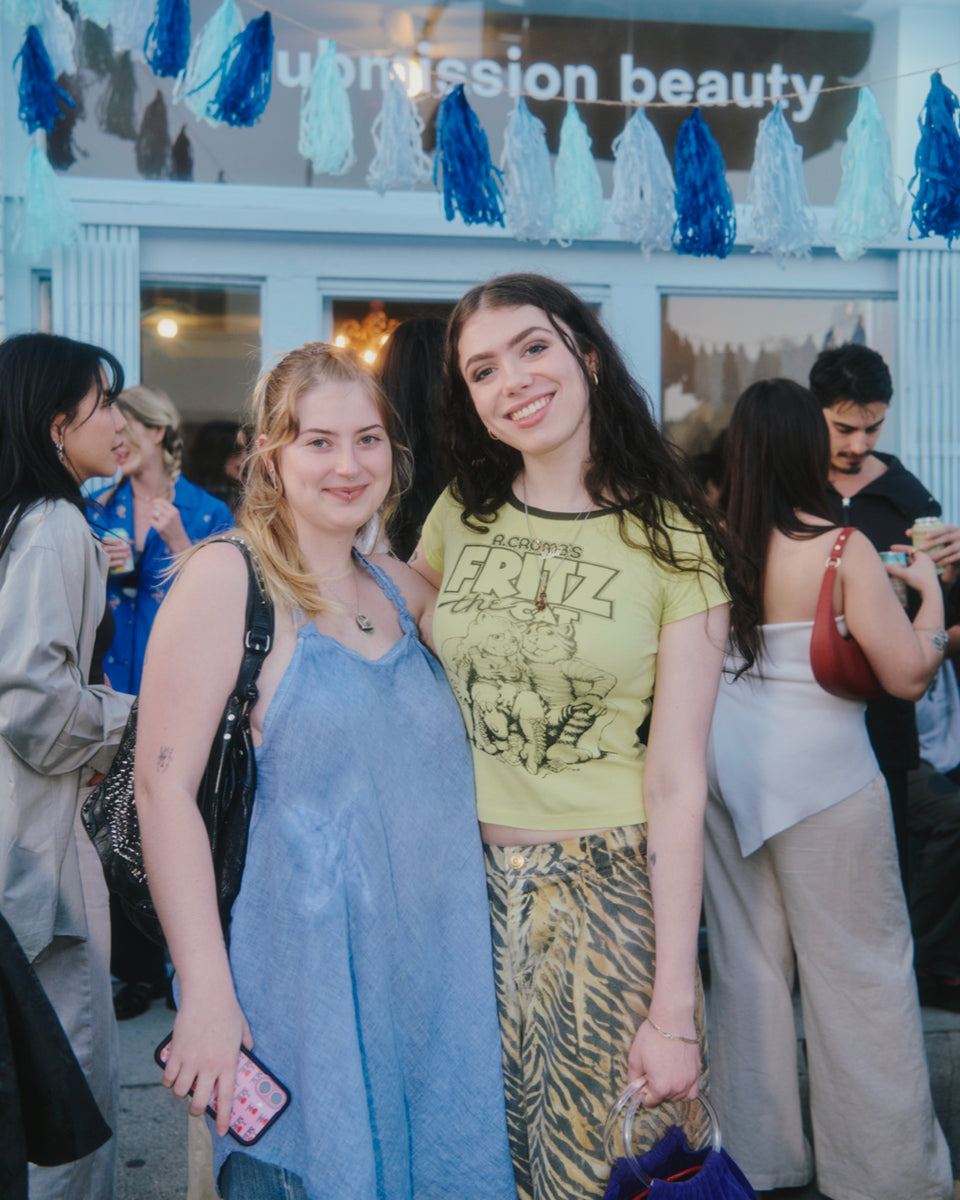Two women posing together in front of a store entrance with decorative elements.