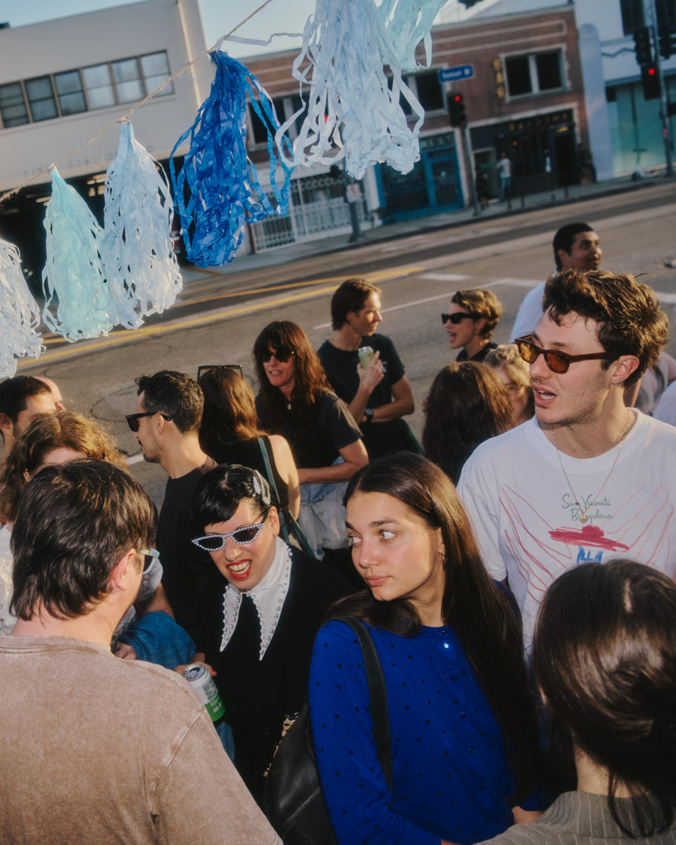 Group of people standing on a street corner with decorative ice sculpture-like structures.