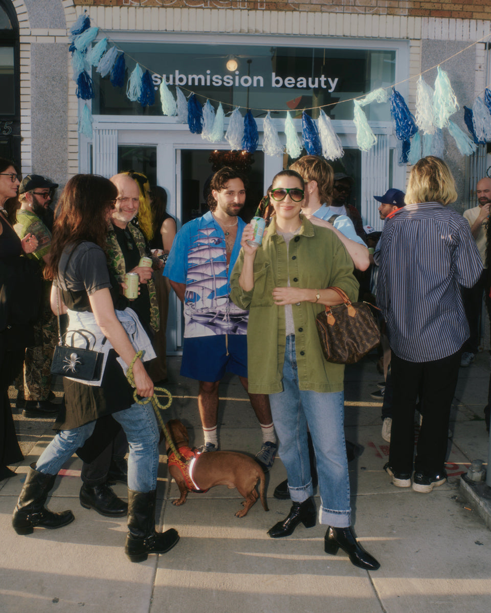 Group of people standing outside a store named 'submission beauty' with decorative elements.