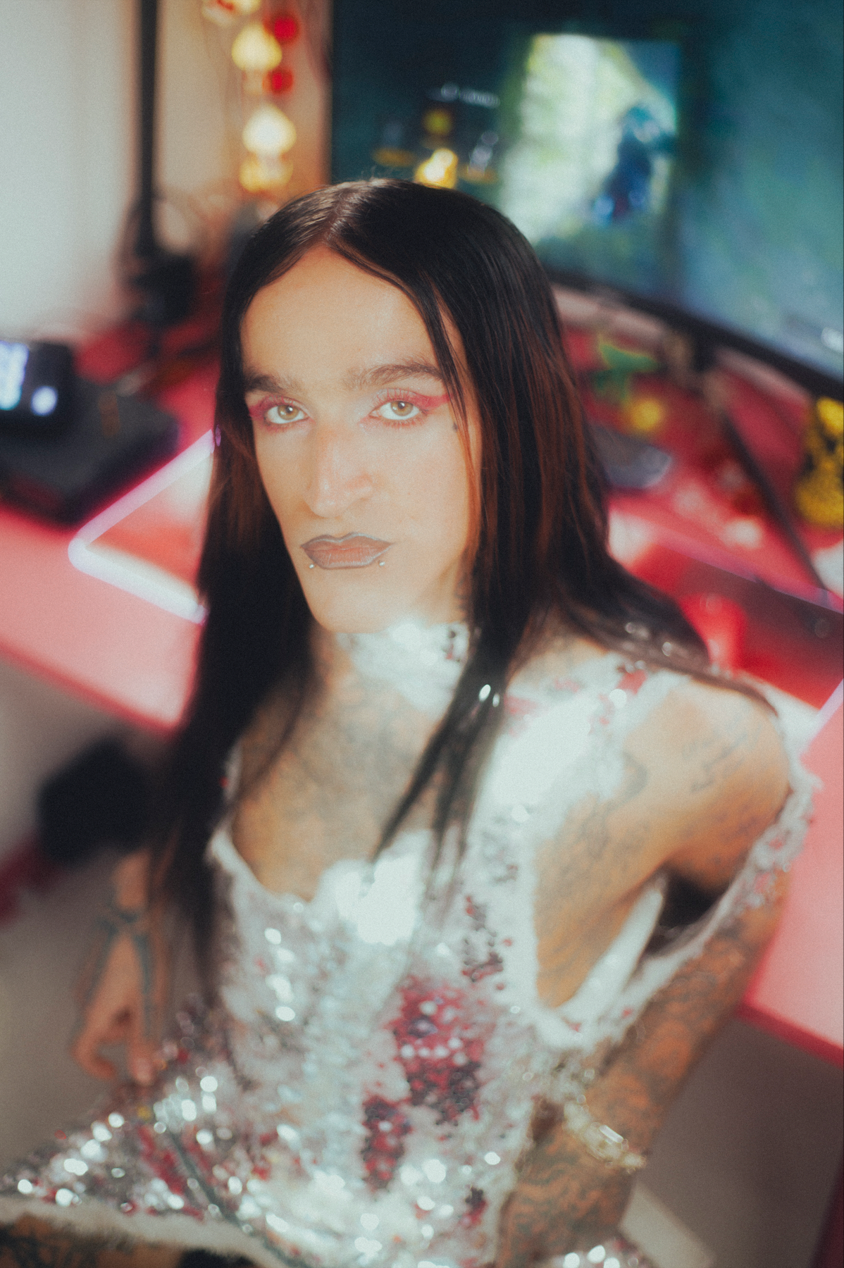 Person wearing a sequined outfit in a room with a blurred background