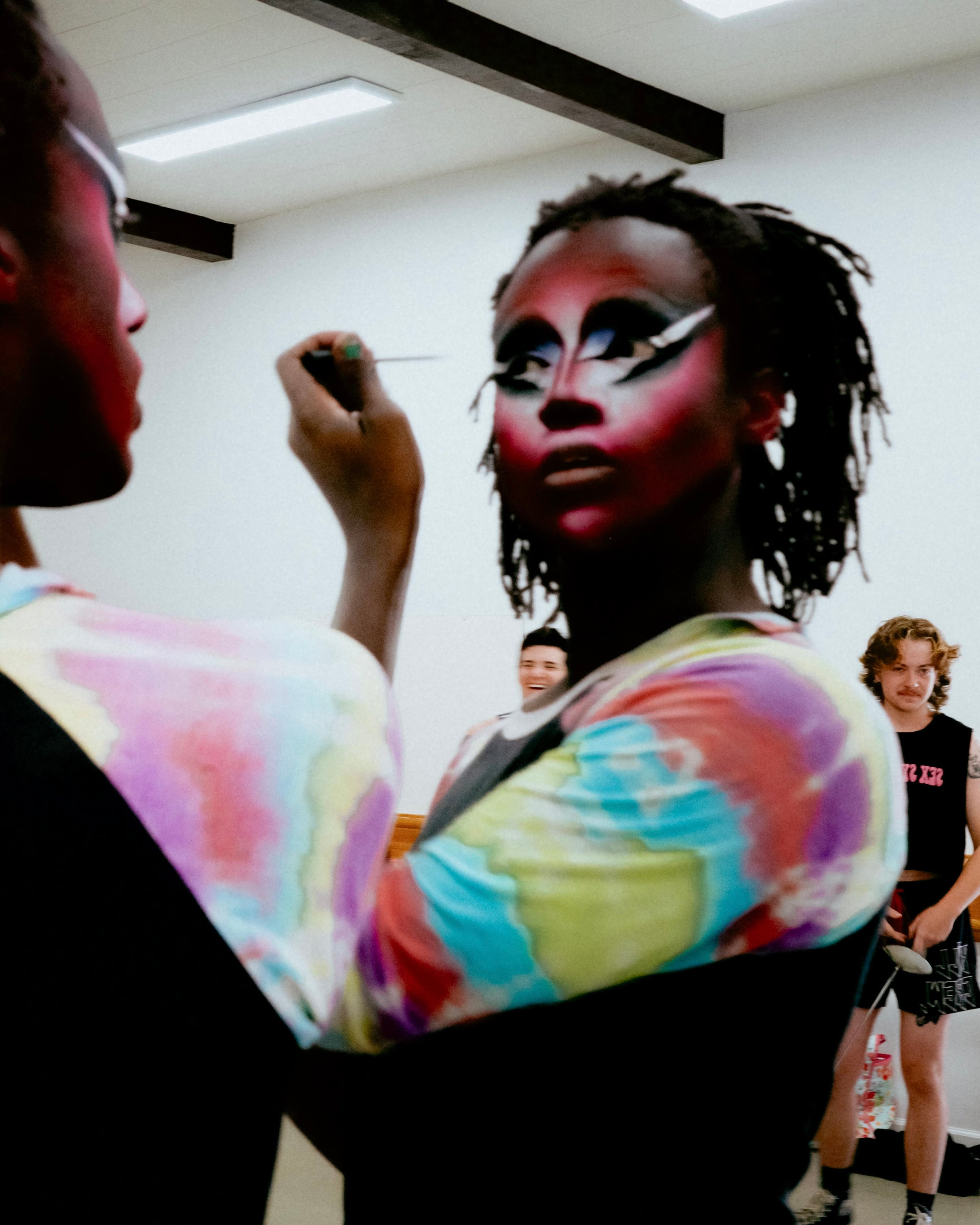 Person with colorful makeup and arm paint in a studio setting.