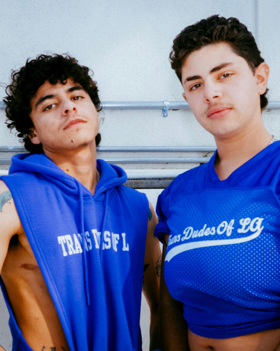Two people wearing blue athletic wear standing outdoors.