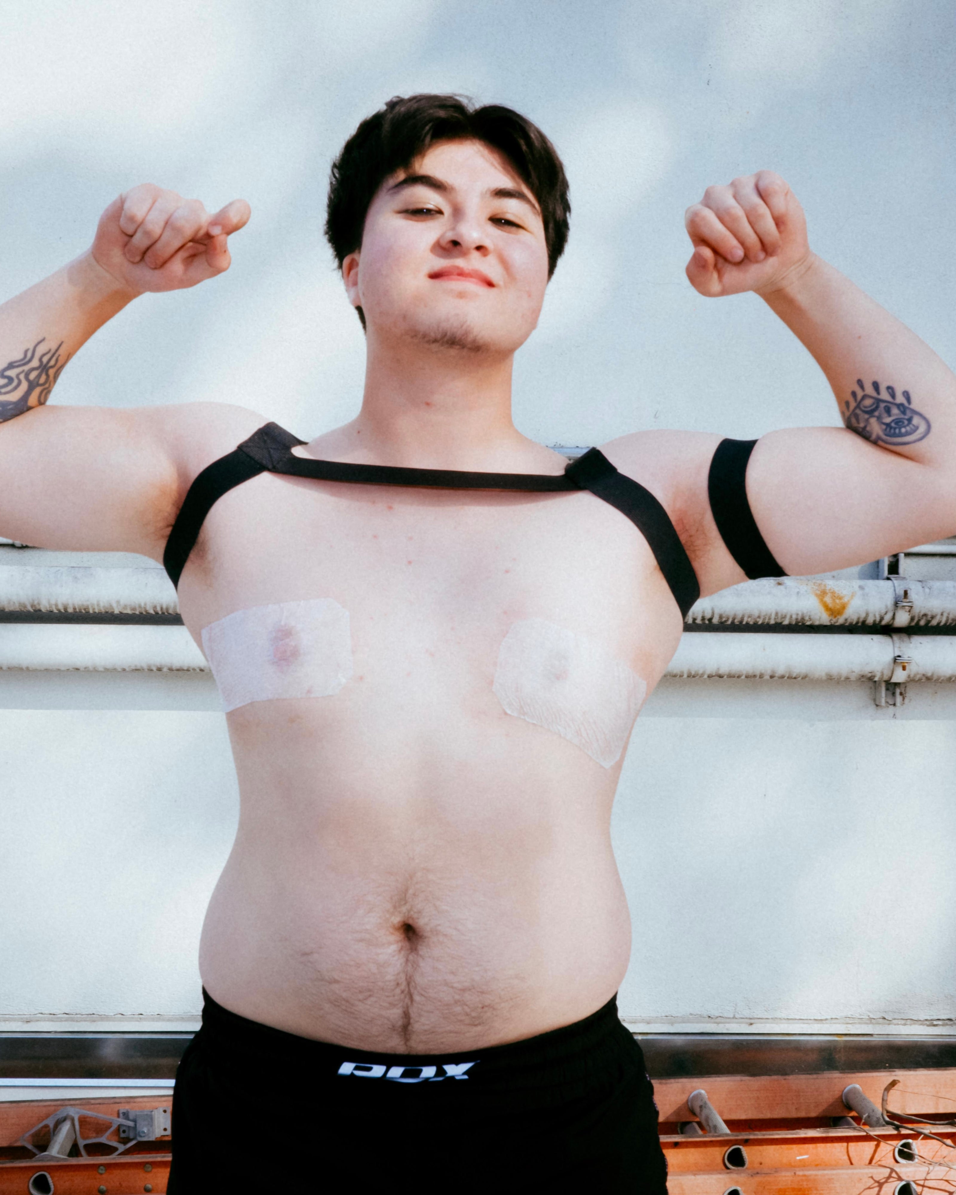 Person wearing a black tank top with a bandage on their chest.