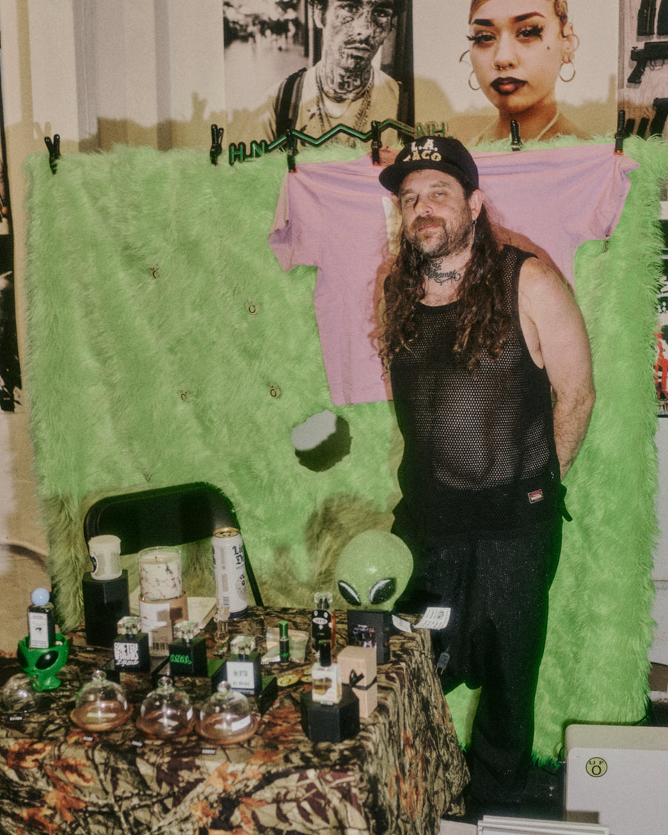 Person standing in front of a display with various items and a green curtain.