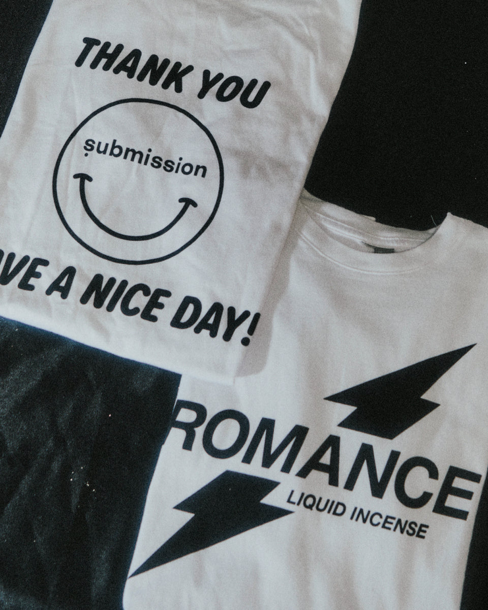 Two white submission beauty t-shirts with black text and graphics on a black background