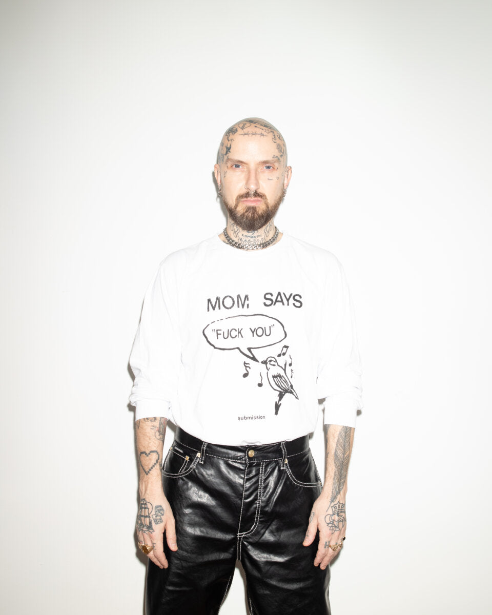 Submission Beauty long-sleeved T-shirt, 100% reclaimed post-industrial waste cotton, made in the USA, featuring a graphic designed by artist B. Thom worn by a male model with light complexion who is bald with a tattooed head with a neutral expression