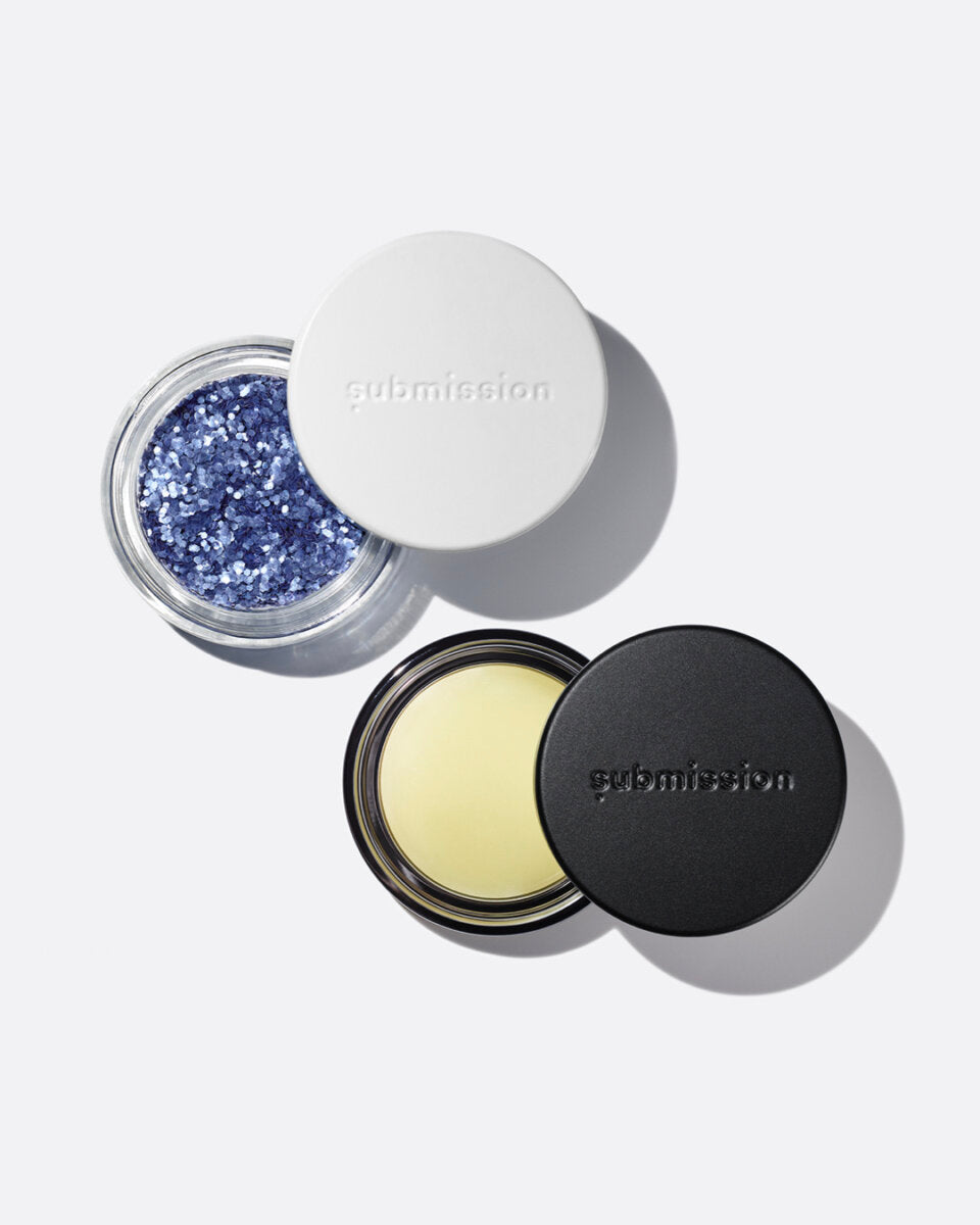 plastic-free plant-based biodegradable blue glitter in an open plastic-free container above an open container of Balm Shiny, a multifunctional plant-based balm intended for all skin types.