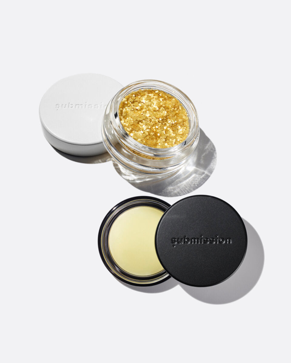 plastic-free plant-based biodegradable gold glitter in an open plastic-free container above an open container of Balm Shiny, a multifunctional plant-based balm intended for all skin types.