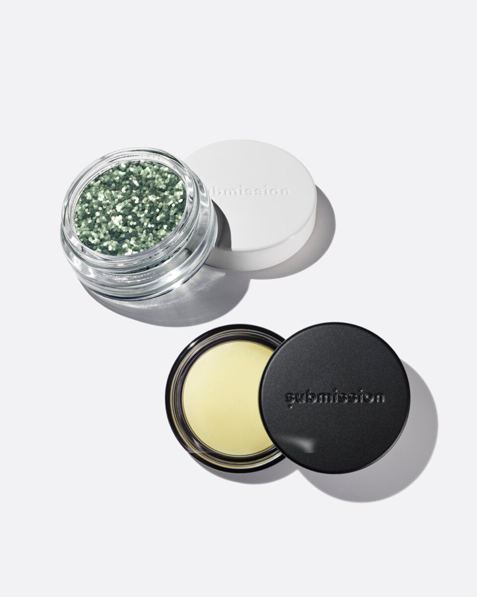 plastic-free plant-based biodegradable green glitter in an open plastic-free container above an open container of Balm Shiny, a multifunctional plant-based balm intended for all skin types.