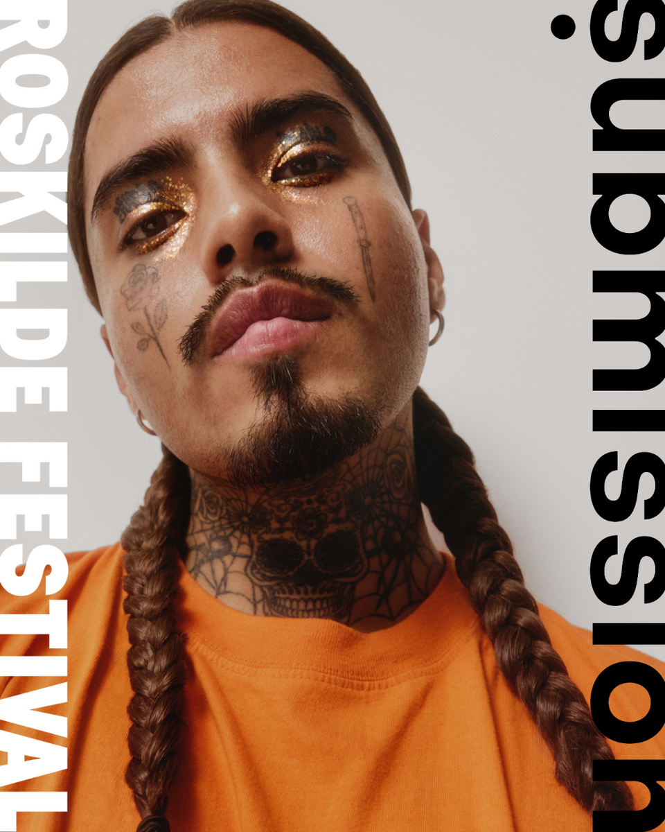 Person with braided hair and tattoos wearing an orange shirt, with text on a light gray background and submission beauty glitter orange on his eyes
