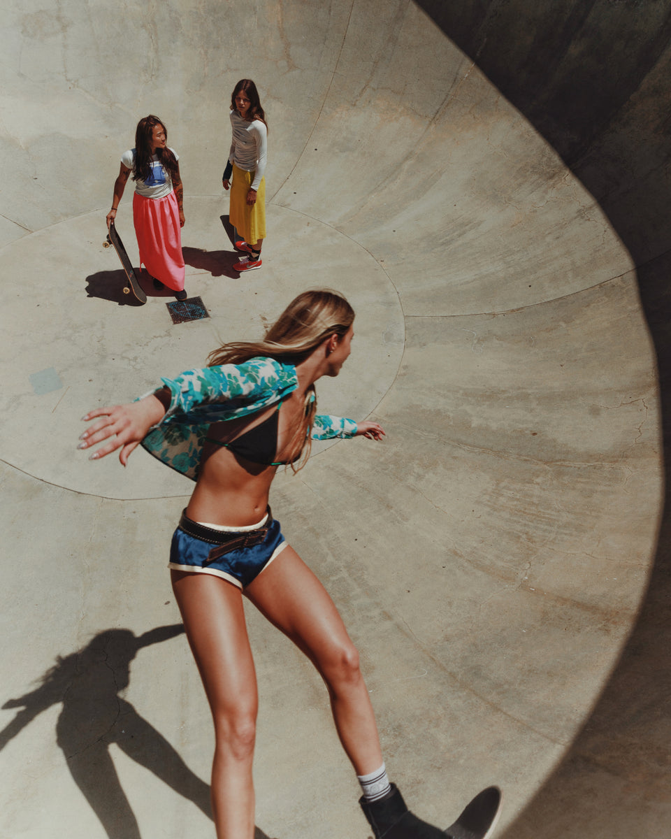 Three women skateboarding in a concrete bowl