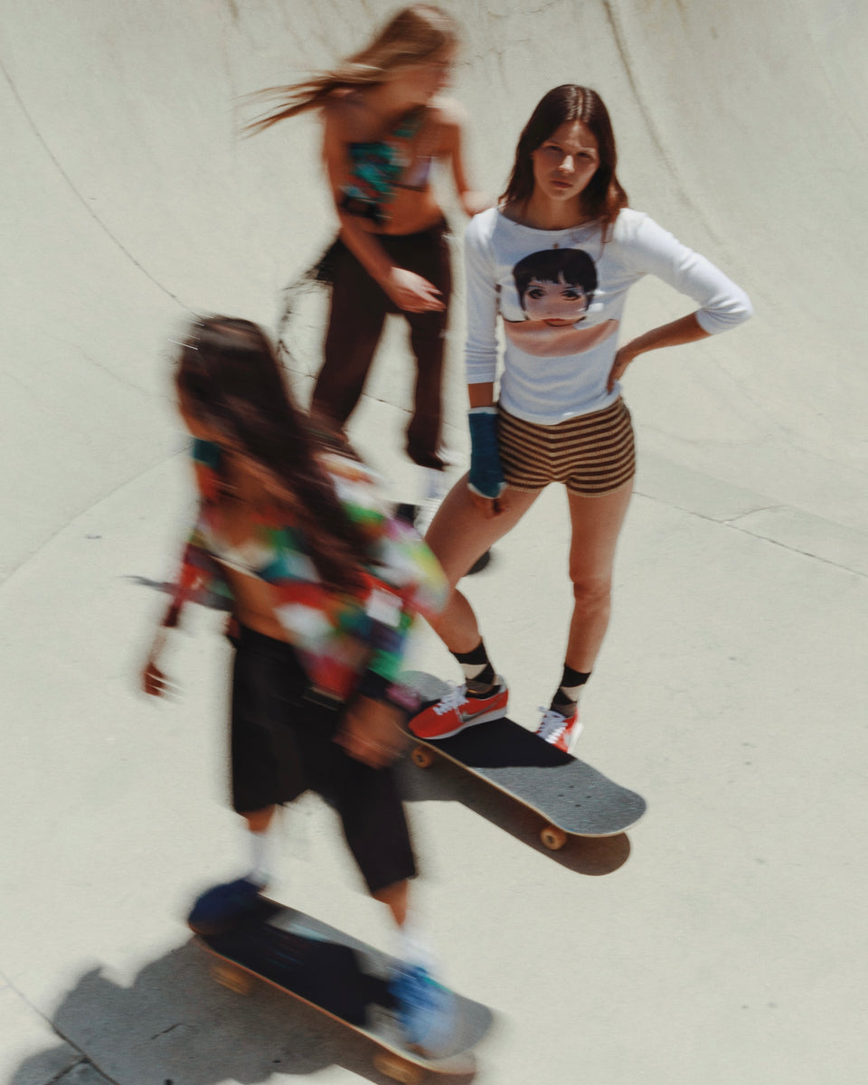 Three people skateboarding on a tiled floor.
