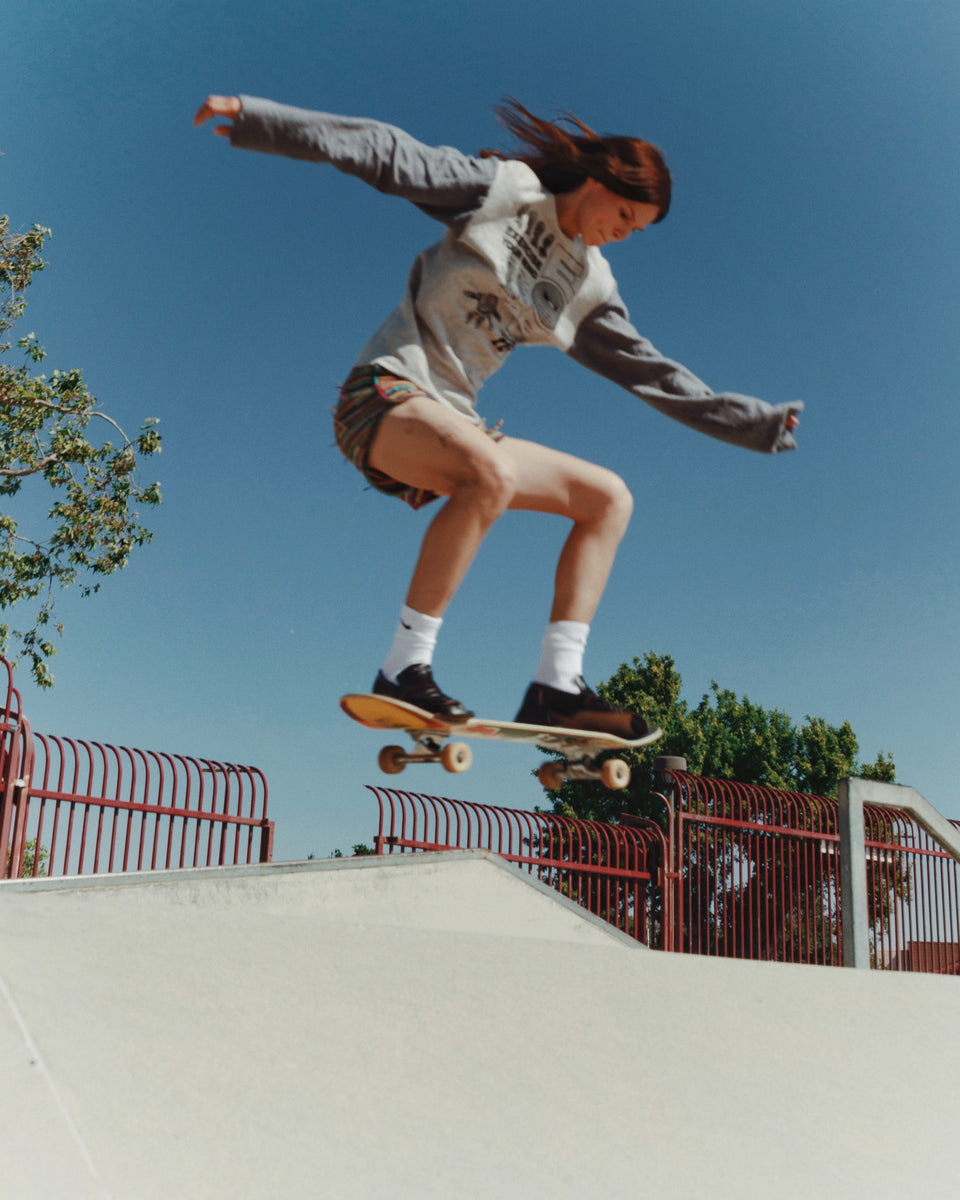Person skateboarding on a ramp with a clear blue sky and trees in the background