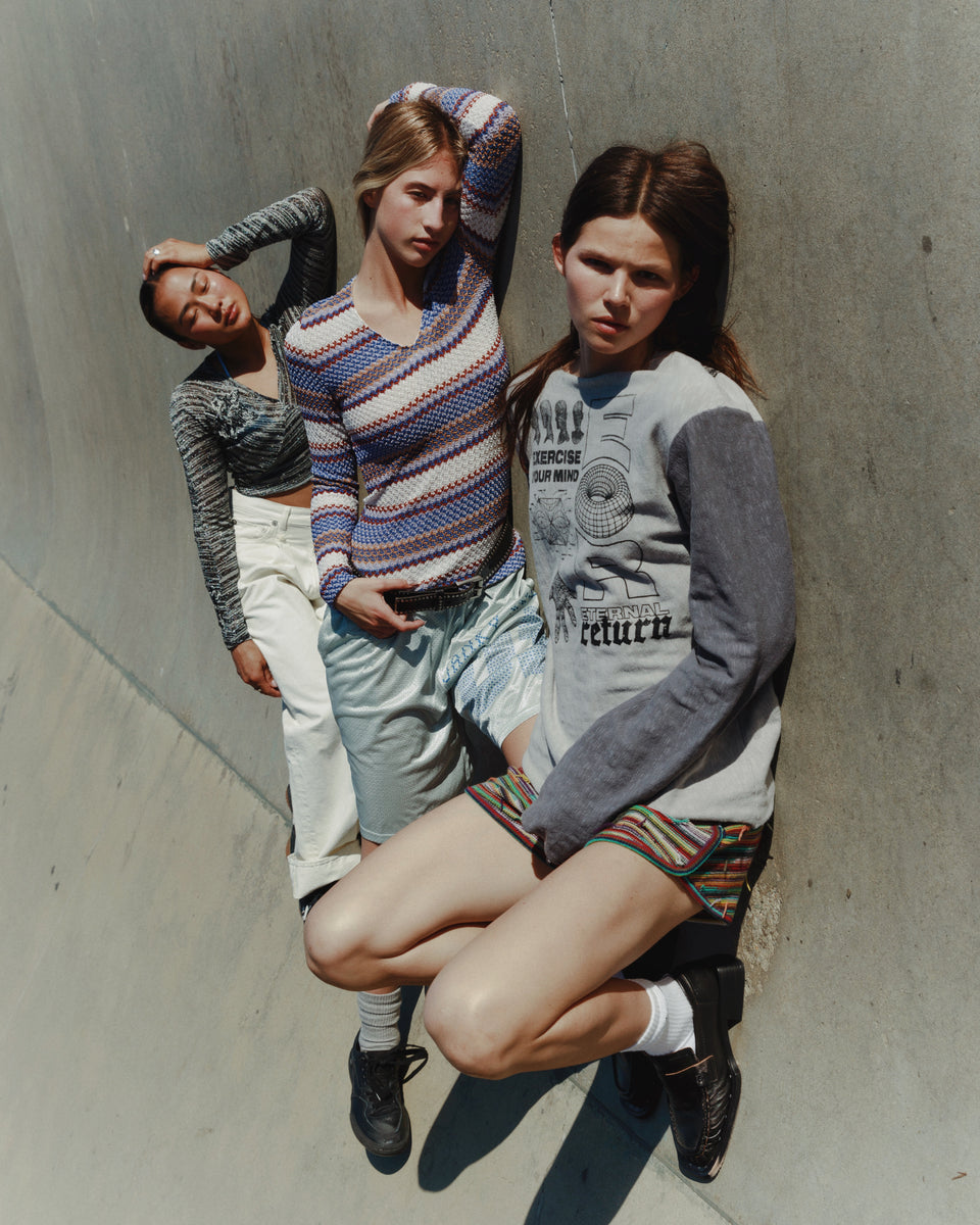 Three people posing against a concrete wall.