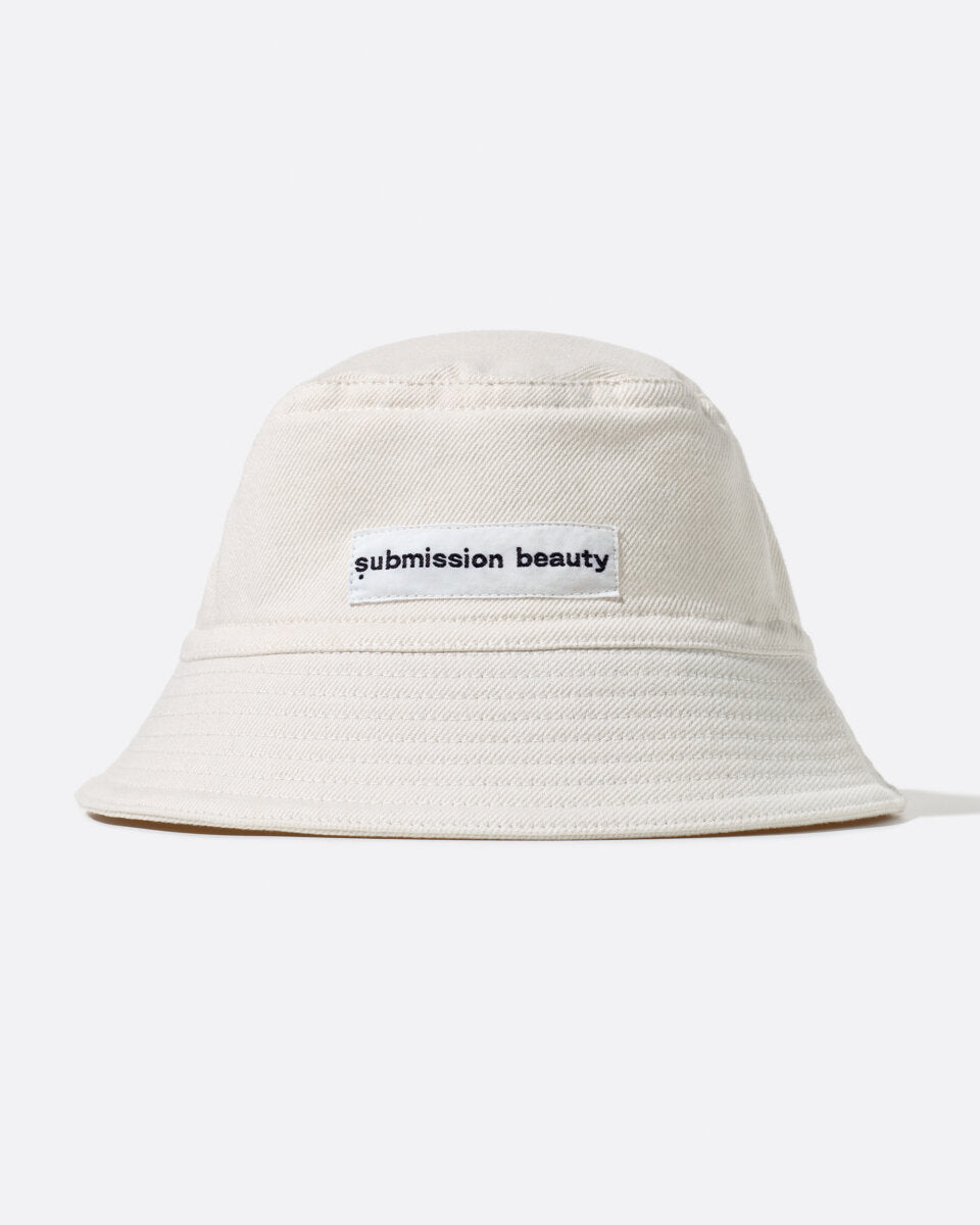 Front view of the submission beauty bucket hat  - an off-white hat featuring a submission beauty label, both made of recycled cotton scraps and sustainably sourced cotton