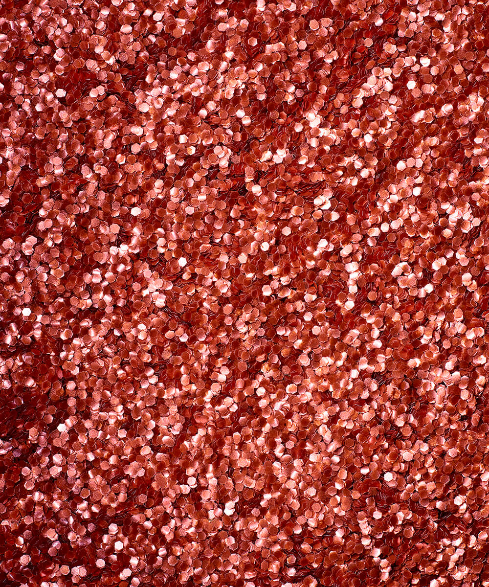 a square, full-bleed overhead view of plastic-free plant-based biodegradable blue glitter flakes highlighting the glitter’s texture and varied shades of red