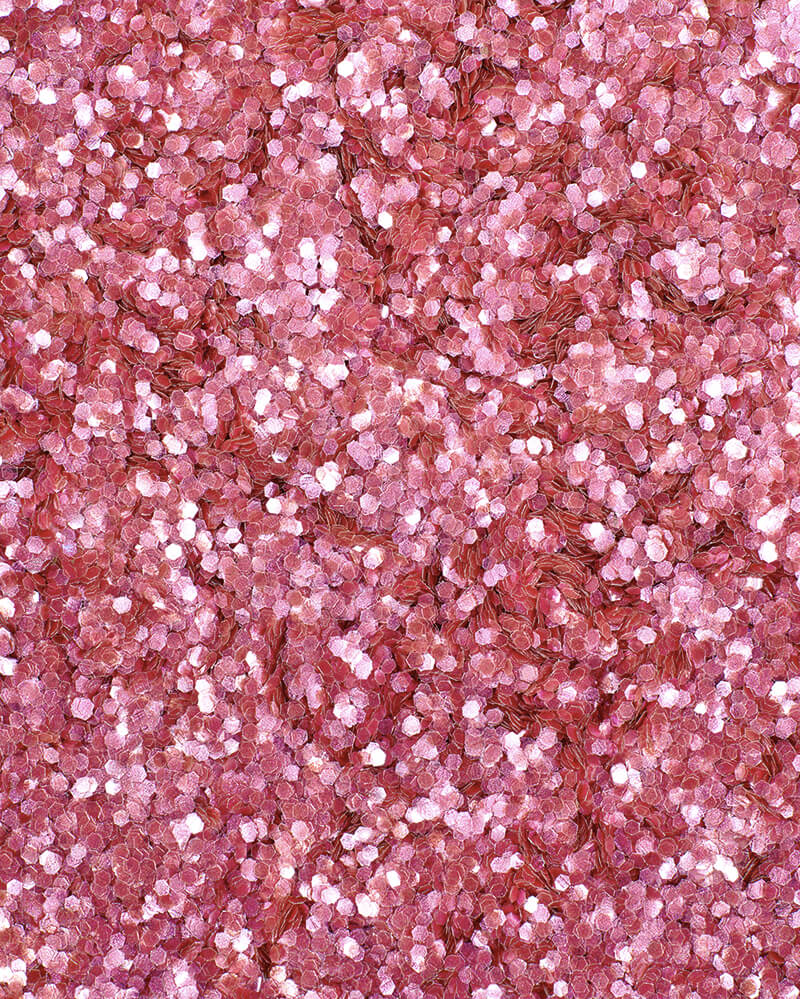 a square, full-bleed overhead view of plastic-free plant-based biodegradable pink glitter flakes highlighting the glitter’s texture and varied shades of pink