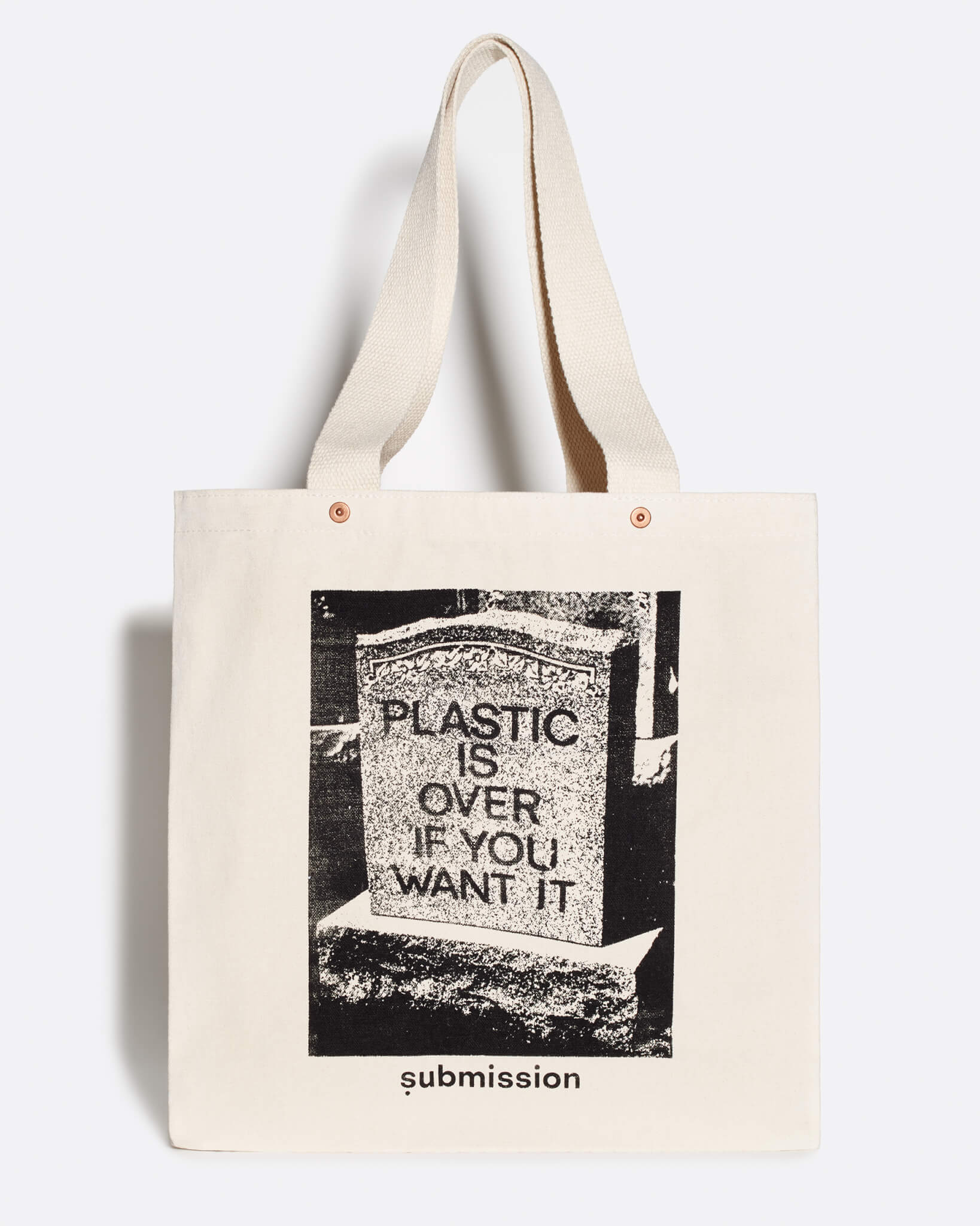 A laydown product shot of a brushed canvas tote bag made with 100% post-consumer recycled cotton, with a flat-bottom design and coppertone metal rivets at the base of the handles, with a large greyscale graphic in the center depicting a headstone with the words “PLASTIC IS OVER IF YOU WANT IT” in capital letters, and a logo beneath the graphic with the word “submission” in bold, lowercase type, all printed with plastic-free ink